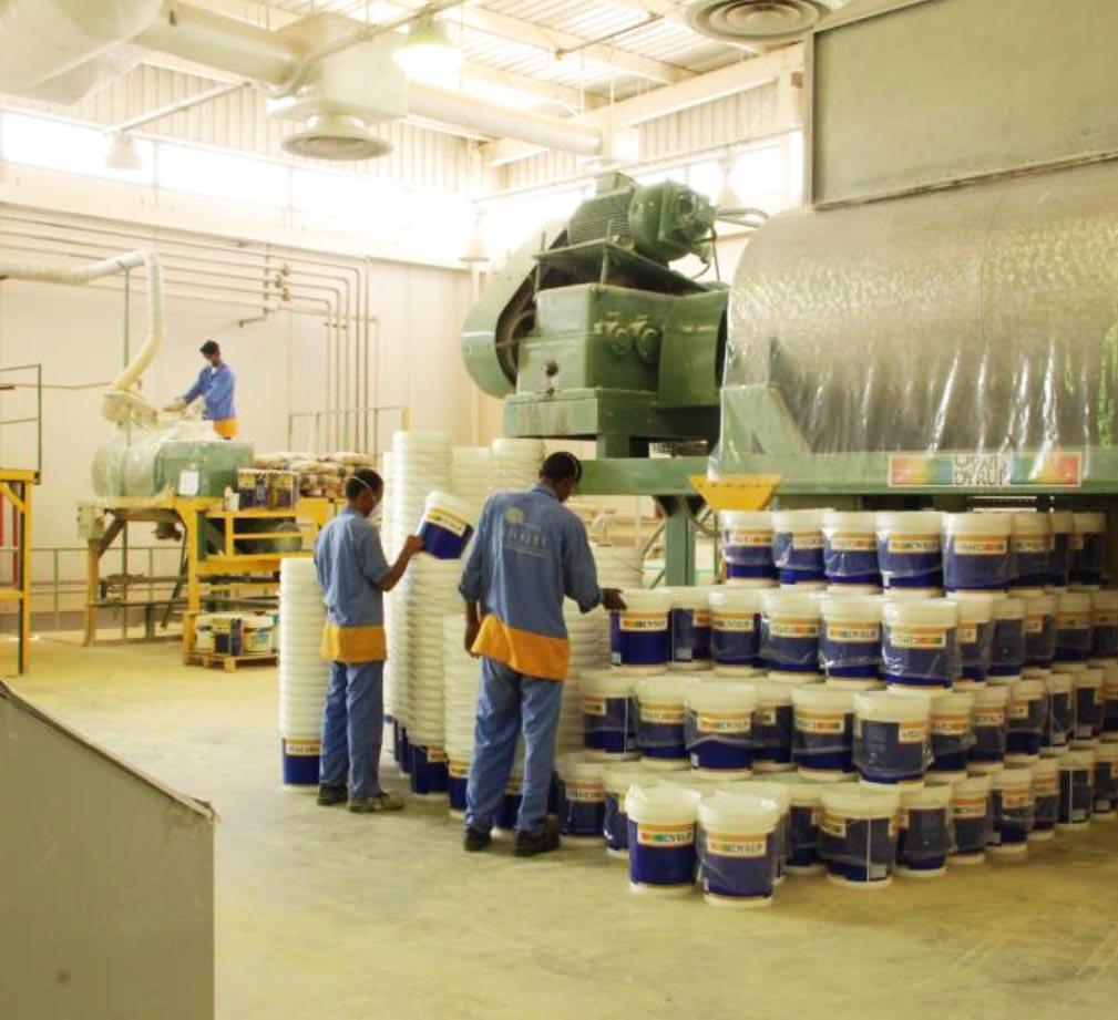 Workers handling paint containers in warehouse